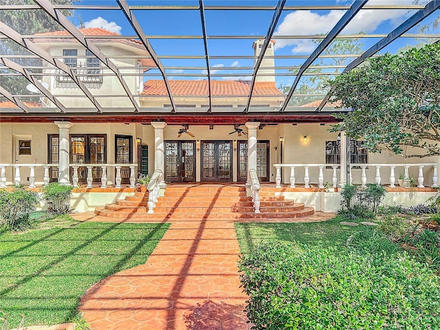 rear view of property with french doors, ceiling fan, a yard, and covered porch