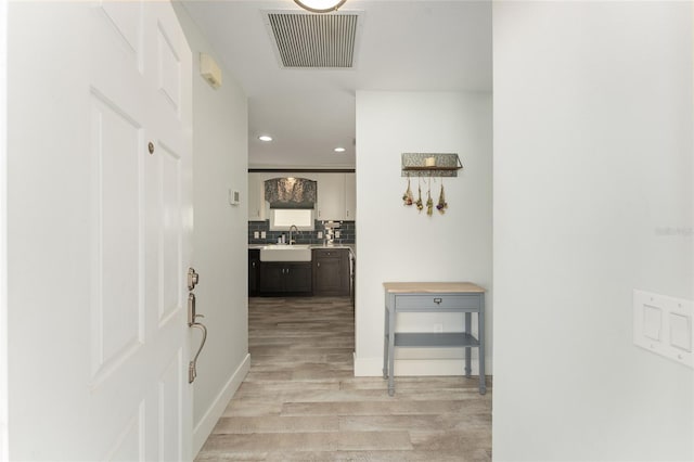 hallway with sink and light hardwood / wood-style flooring