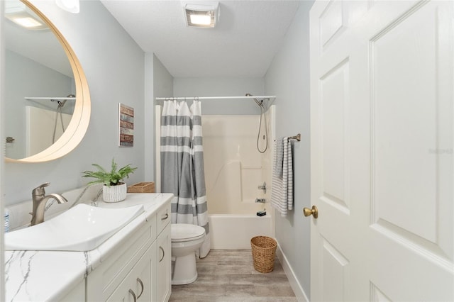 full bathroom with hardwood / wood-style floors, shower / bath combination with curtain, vanity, toilet, and a textured ceiling