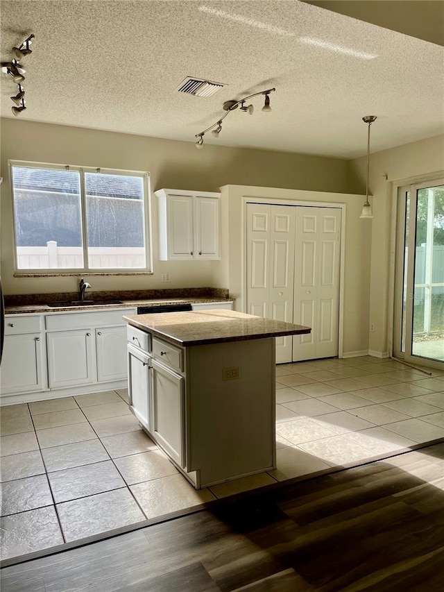 kitchen with sink, a kitchen island, white cabinetry, and pendant lighting