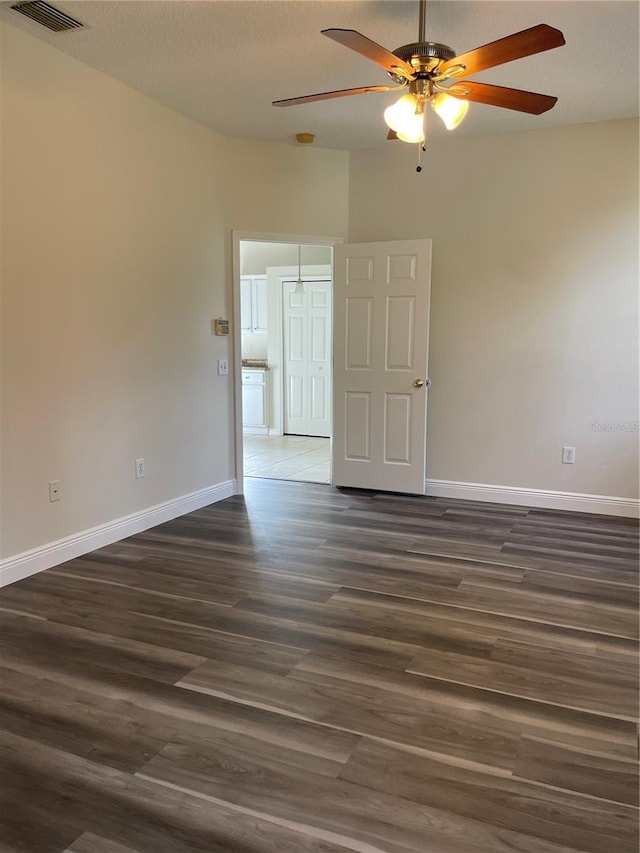 empty room with ceiling fan and dark hardwood / wood-style flooring