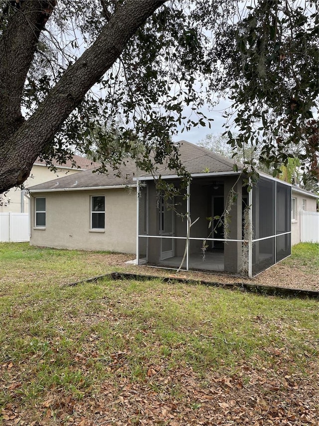 rear view of house with a lawn and a sunroom