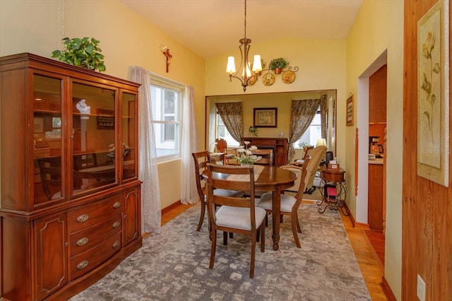 dining area featuring a chandelier, light hardwood / wood-style flooring, and vaulted ceiling