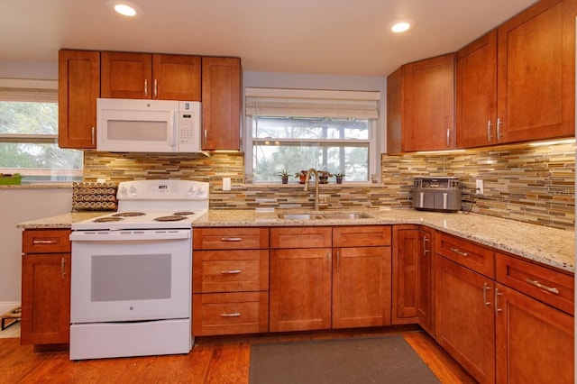 kitchen with white appliances, sink, light hardwood / wood-style flooring, backsplash, and light stone counters