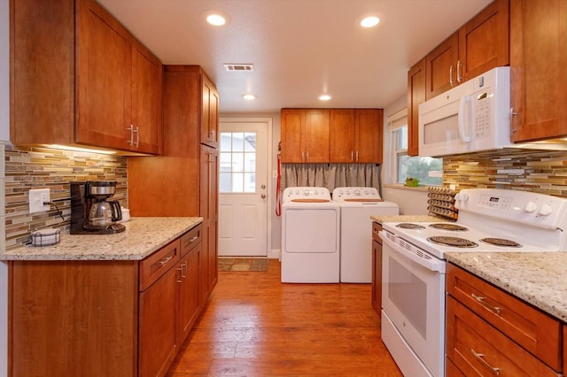 kitchen with white appliances, light wood-type flooring, plenty of natural light, and washing machine and clothes dryer