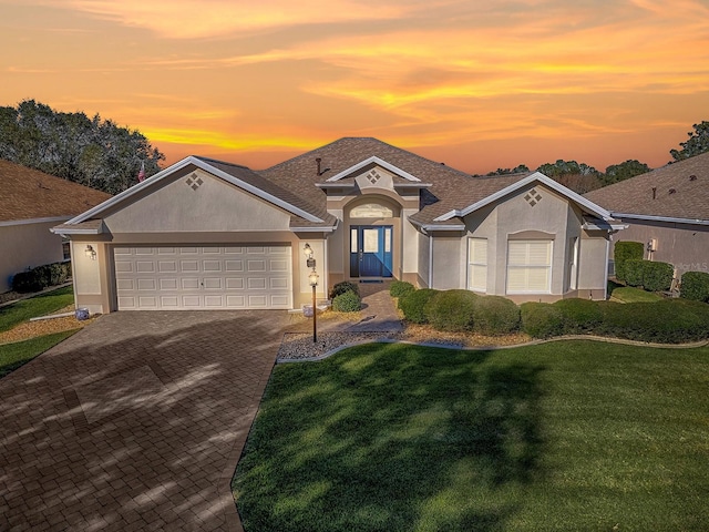 single story home featuring a garage and a yard