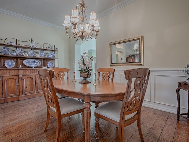 dining space featuring a notable chandelier, ornamental molding, and light wood-type flooring