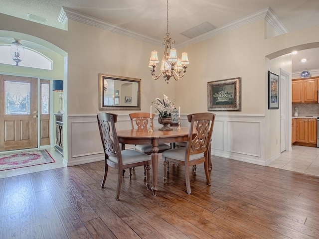 dining area with crown molding, light hardwood / wood-style floors, and a notable chandelier