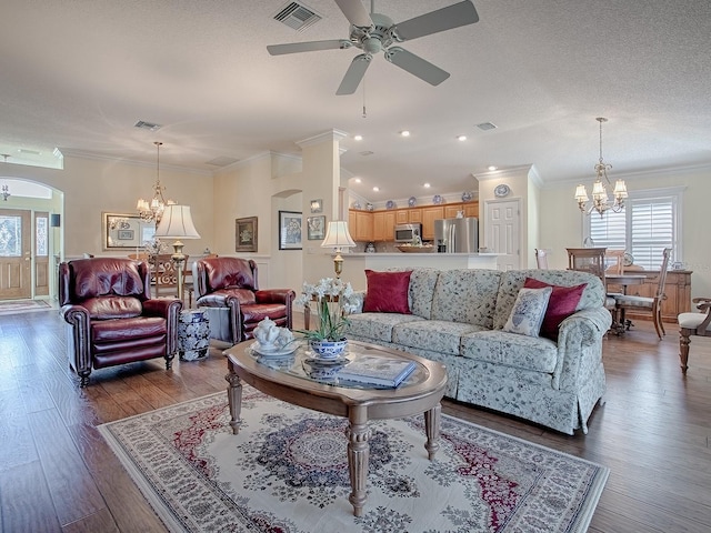 living room featuring ornamental molding, dark hardwood / wood-style flooring, ceiling fan with notable chandelier, and a textured ceiling