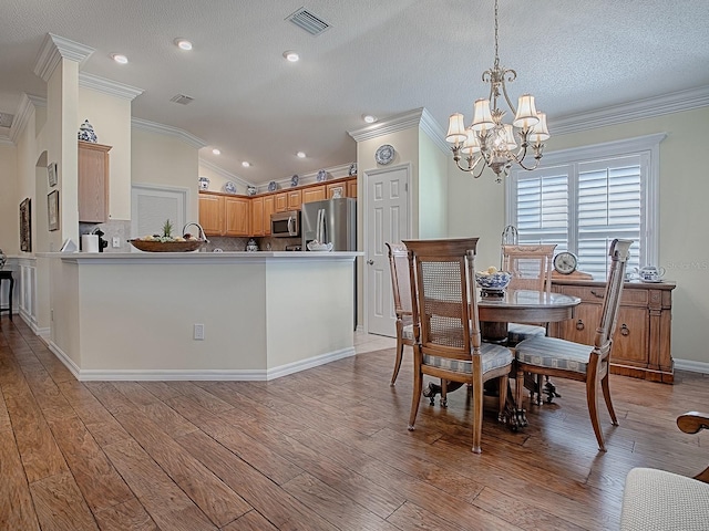 dining room with crown molding, light hardwood / wood-style floors, a textured ceiling, vaulted ceiling, and a chandelier