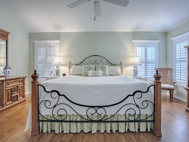 bedroom with hardwood / wood-style flooring, a textured ceiling, and ceiling fan