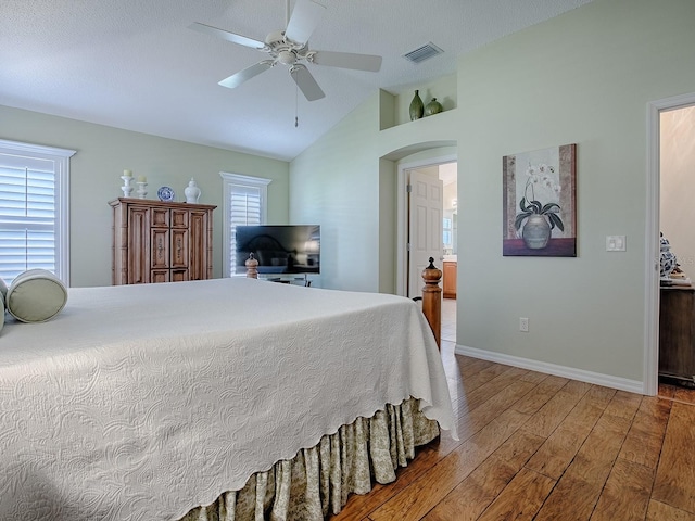 bedroom with ceiling fan, ensuite bathroom, multiple windows, and light wood-type flooring