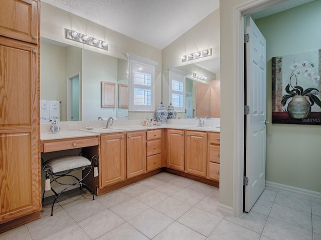 bathroom featuring vanity, lofted ceiling, tile patterned floors, and a textured ceiling