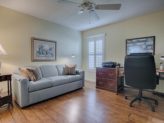 home office featuring ceiling fan, light hardwood / wood-style flooring, and a textured ceiling