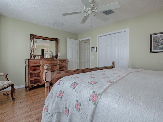 bedroom with a textured ceiling, ceiling fan, and light hardwood / wood-style floors