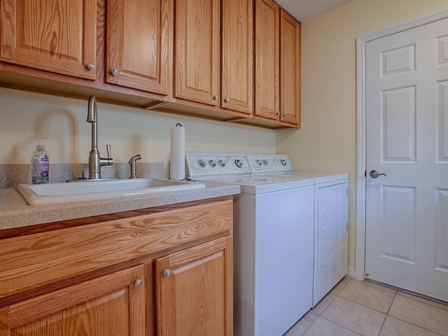 clothes washing area with cabinets, washing machine and dryer, sink, and light tile patterned floors