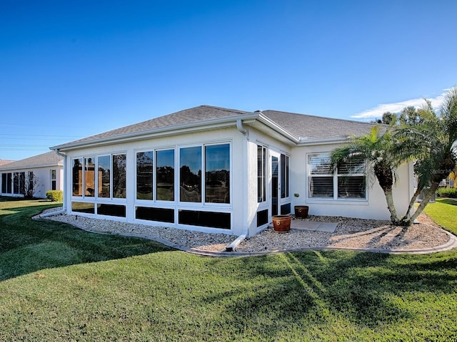 rear view of house featuring a lawn and a sunroom