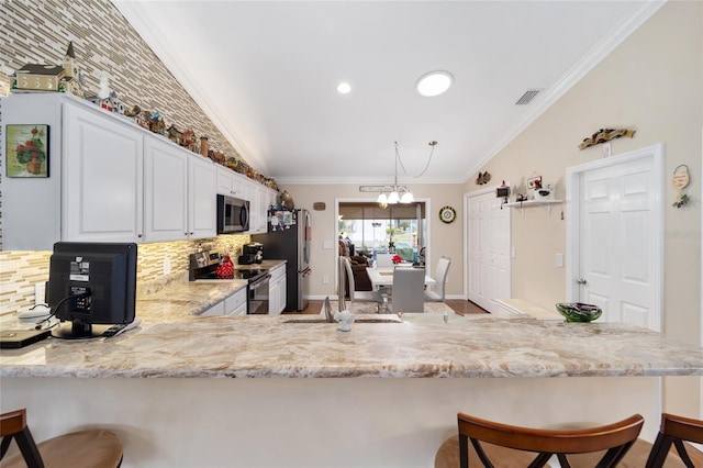 kitchen featuring appliances with stainless steel finishes, white cabinetry, a sink, a peninsula, and a kitchen breakfast bar