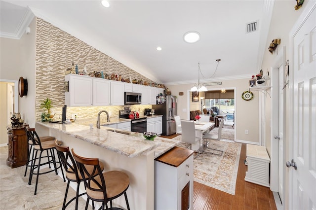 kitchen with a peninsula, a sink, visible vents, white cabinetry, and appliances with stainless steel finishes