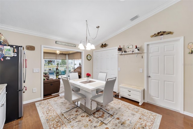 dining space with a chandelier, vaulted ceiling, dark hardwood / wood-style floors, and ornamental molding