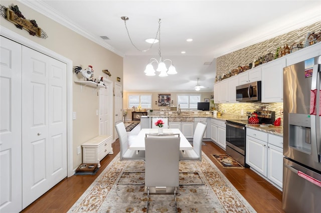 kitchen featuring white cabinets, a kitchen breakfast bar, a peninsula, stainless steel appliances, and light countertops