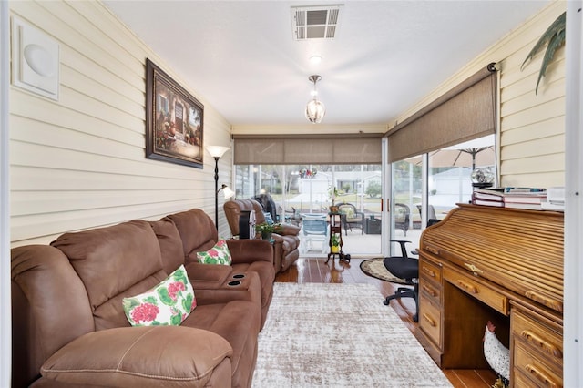 living area featuring a sunroom, visible vents, and wood finished floors