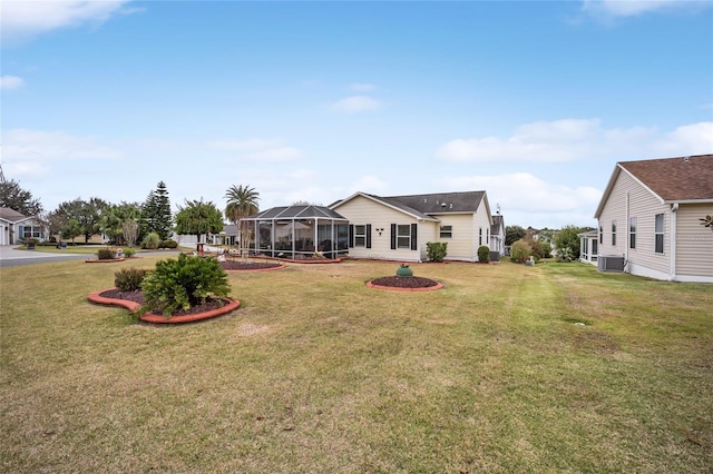 rear view of property with a residential view, glass enclosure, a lawn, and central AC