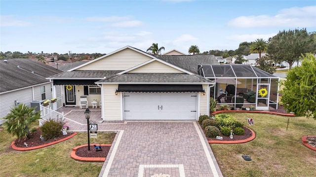 ranch-style home featuring decorative driveway, a front yard, a lanai, and roof with shingles