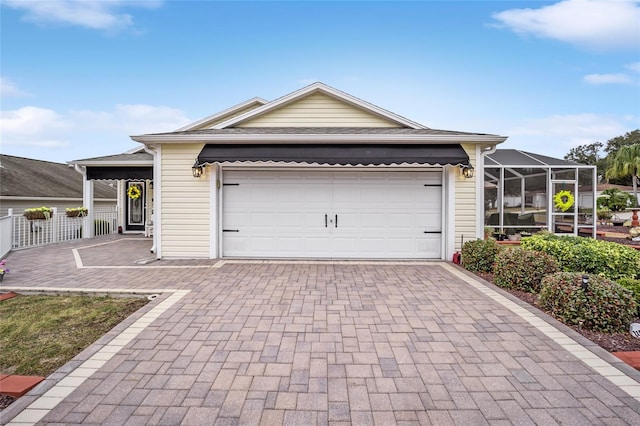 ranch-style home with an attached garage, glass enclosure, and decorative driveway