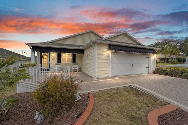 single story home with an attached garage, covered porch, and decorative driveway