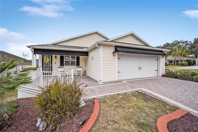 single story home featuring a porch, decorative driveway, and an attached garage