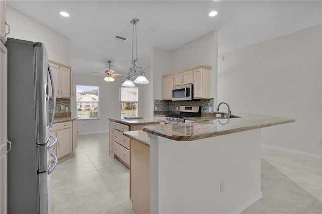 kitchen with sink, appliances with stainless steel finishes, kitchen peninsula, light stone countertops, and decorative backsplash