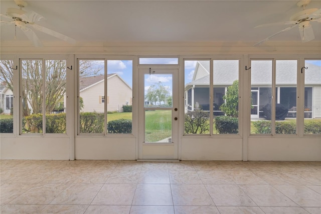 unfurnished sunroom featuring ceiling fan and a wealth of natural light