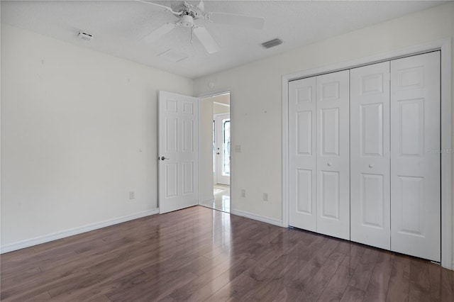 unfurnished bedroom with dark wood-type flooring, ceiling fan, a closet, and a textured ceiling