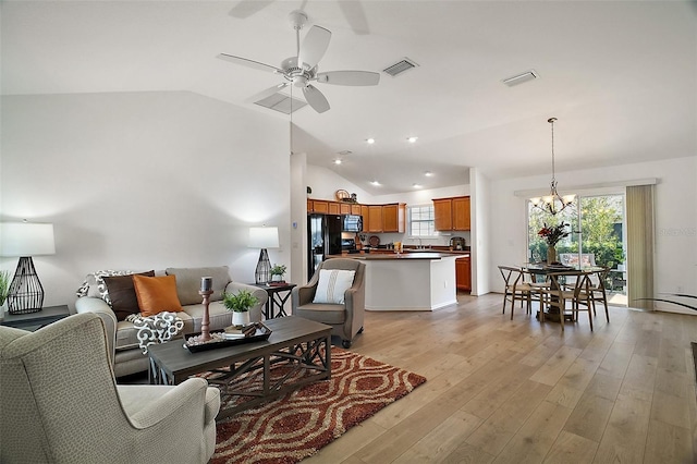 living room featuring ceiling fan with notable chandelier, lofted ceiling, a wealth of natural light, and light wood-type flooring