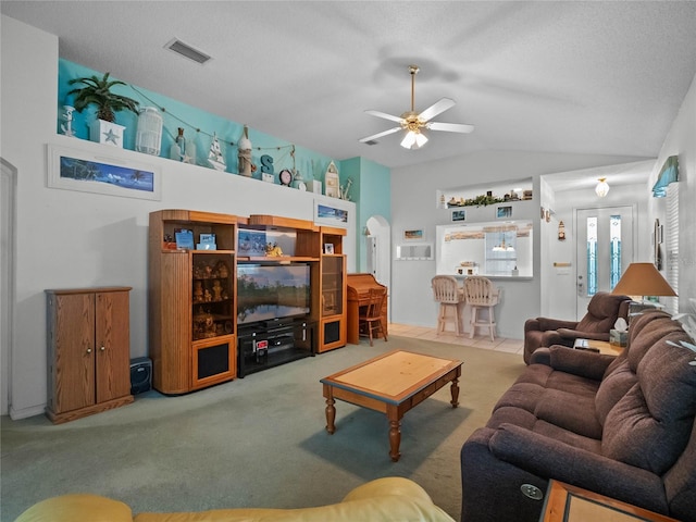 living room with ceiling fan, lofted ceiling, carpet flooring, and a textured ceiling