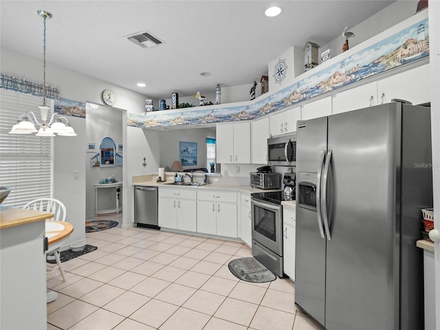 kitchen featuring light tile patterned floors, sink, appliances with stainless steel finishes, hanging light fixtures, and white cabinets