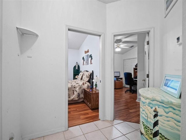 corridor with light tile patterned flooring and vaulted ceiling