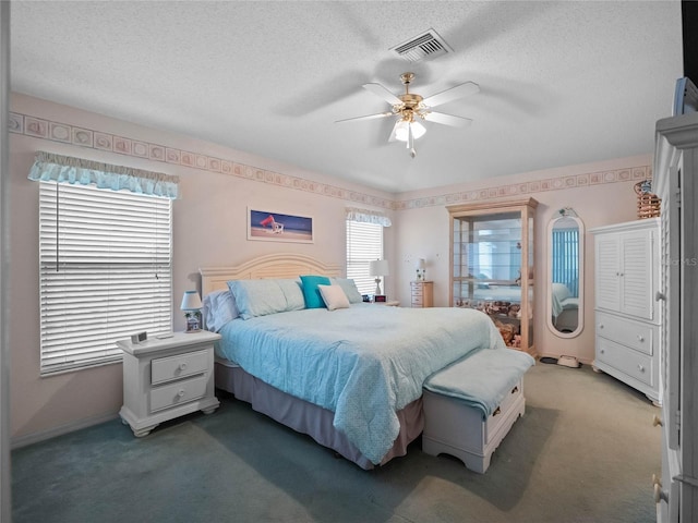 bedroom featuring a textured ceiling, ceiling fan, and dark colored carpet