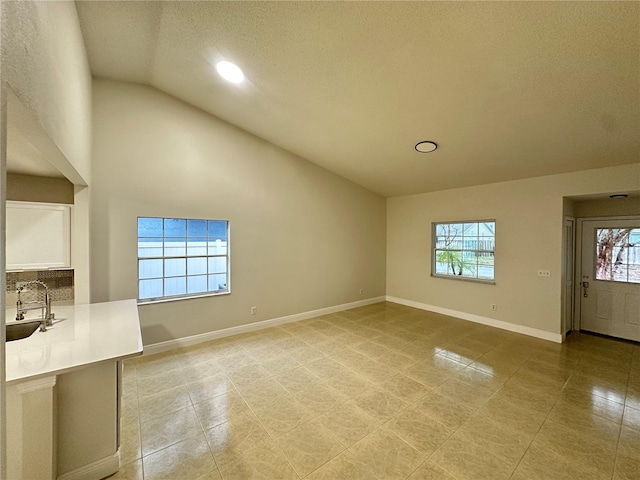 unfurnished living room featuring sink, light tile patterned floors, high vaulted ceiling, and a textured ceiling