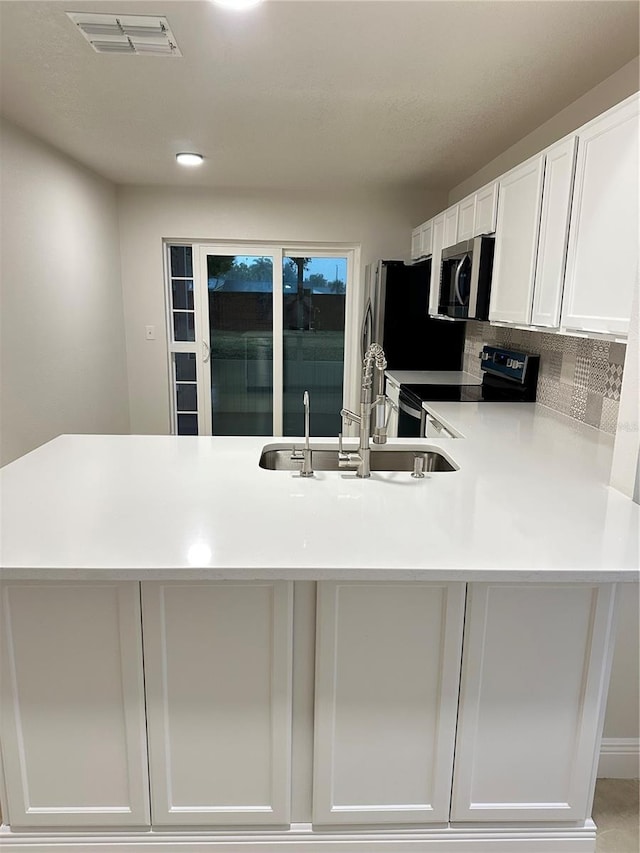 kitchen with sink, white cabinetry, light tile patterned floors, black range with electric stovetop, and decorative backsplash