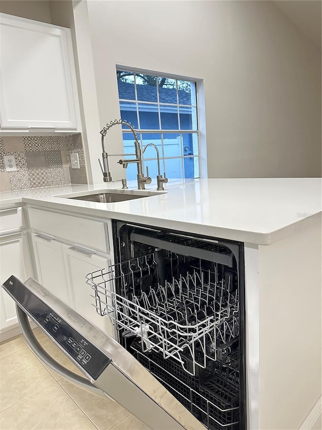 room details with white cabinetry, dishwashing machine, sink, and backsplash