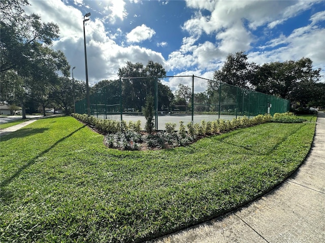 view of tennis court featuring a yard