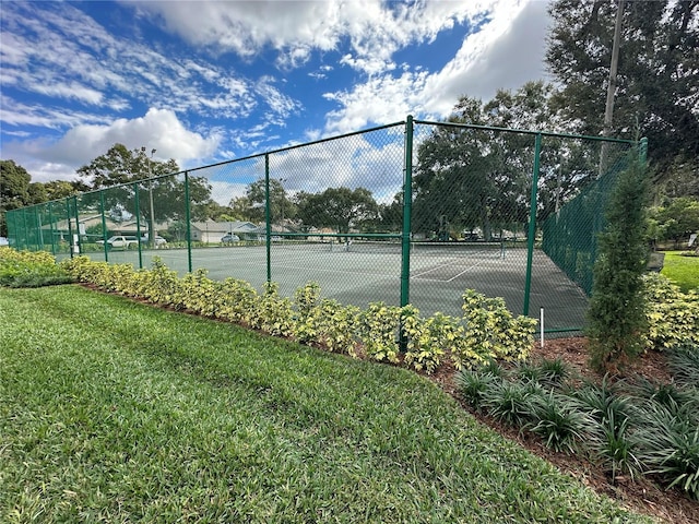 view of tennis court featuring a yard