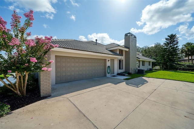 view of front of house featuring cooling unit, a garage, and a front lawn