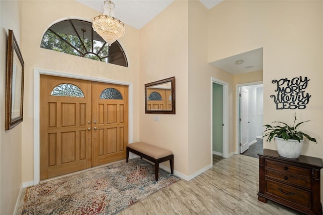 entrance foyer with an inviting chandelier, a towering ceiling, and light hardwood / wood-style floors