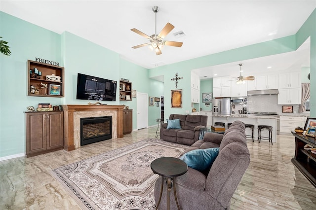 living room featuring a high end fireplace and ceiling fan