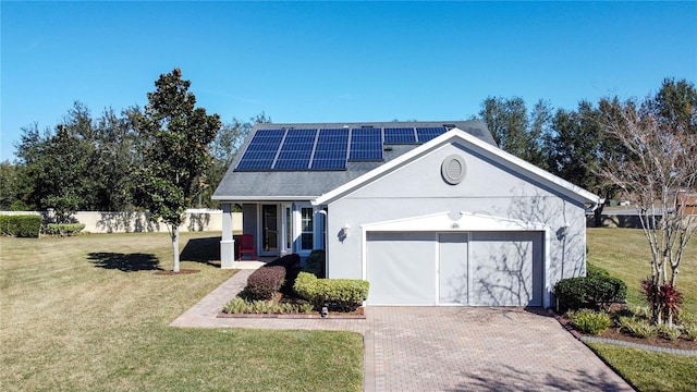 view of front of property with a garage, a front yard, and solar panels