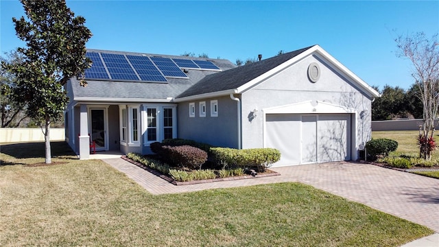 view of front of property with a garage, a front lawn, and solar panels