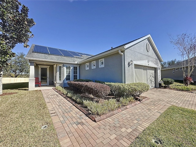 single story home with a garage, a front yard, and solar panels